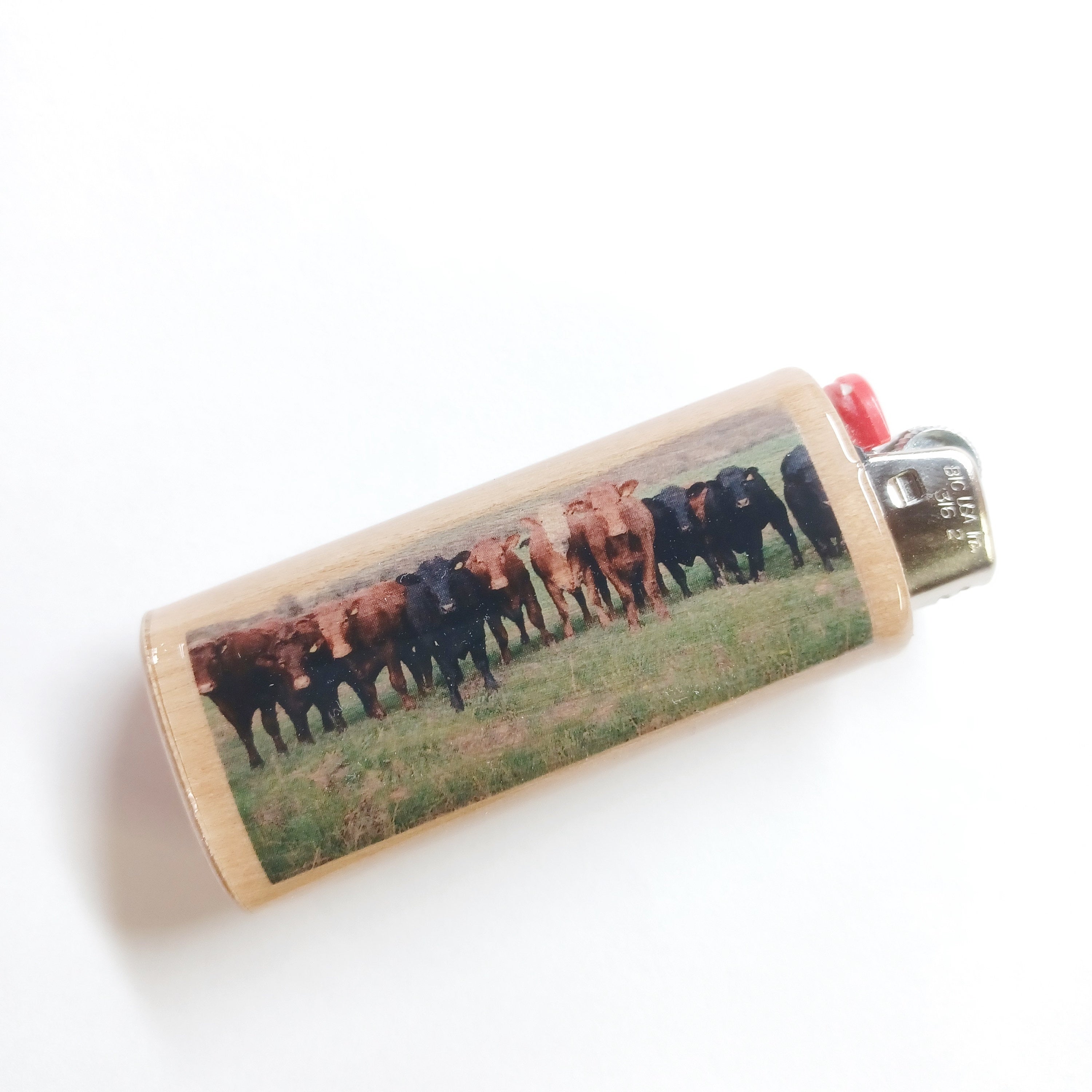 Lighter with a printed design of cows on a grassy field