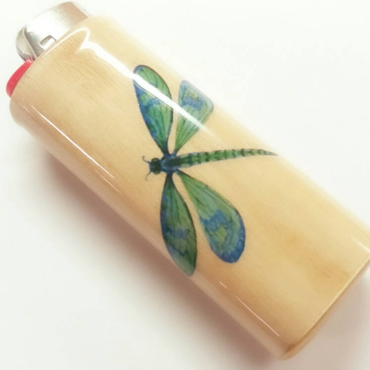 Lighter with a green dragonfly design on a beige background