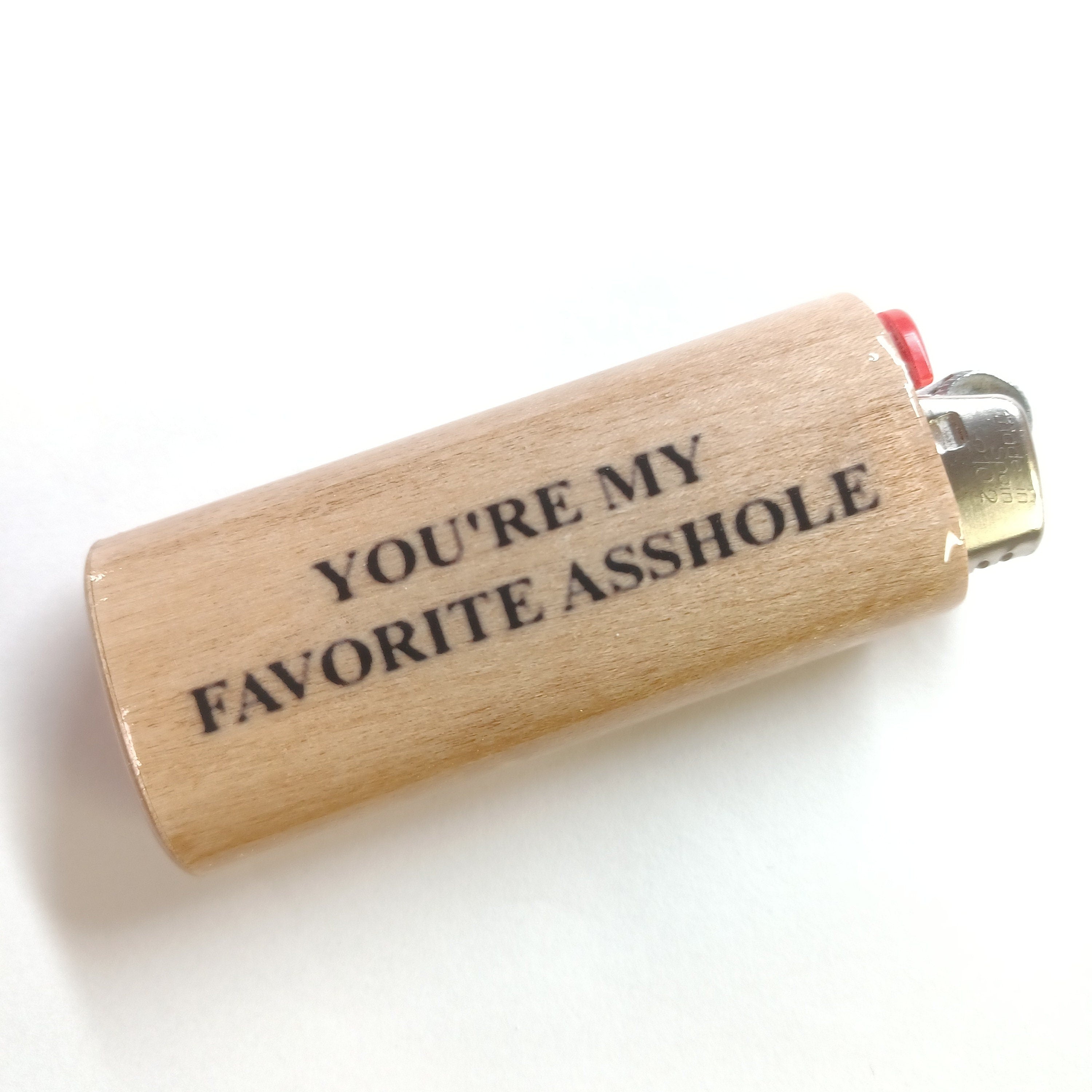 Lighter with text 'YOU'RE MY FAVORITE ASSHOLE' on a white background