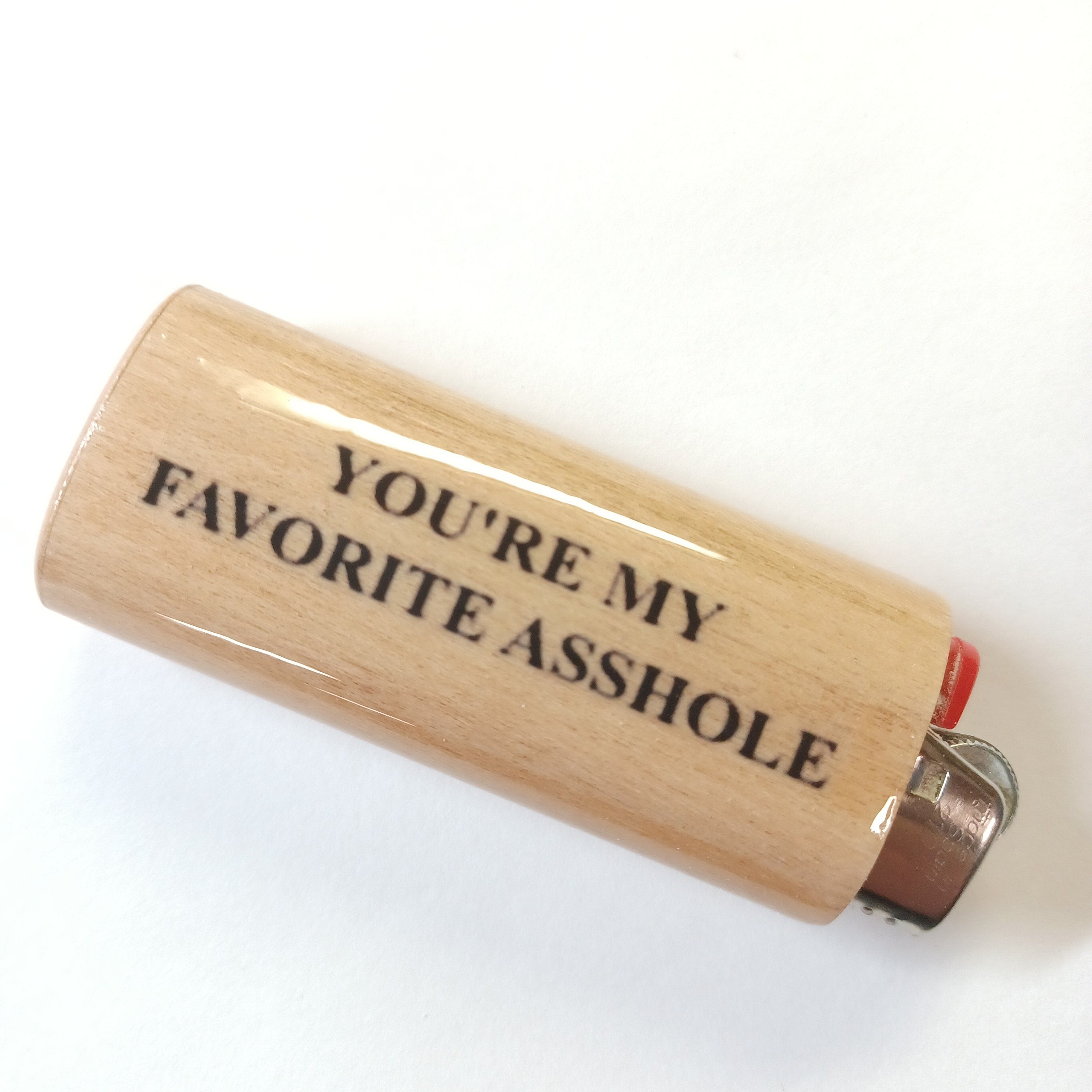 Wooden lighter with text 'YOU'RE MY FAVORITE ASSHOLE' on a white background