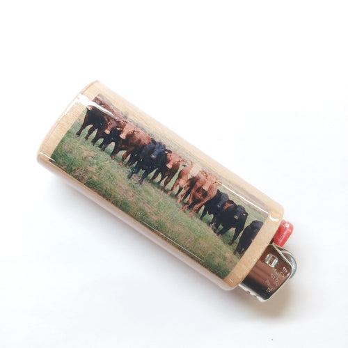 Lighter with a printed design of cows on a grassy field