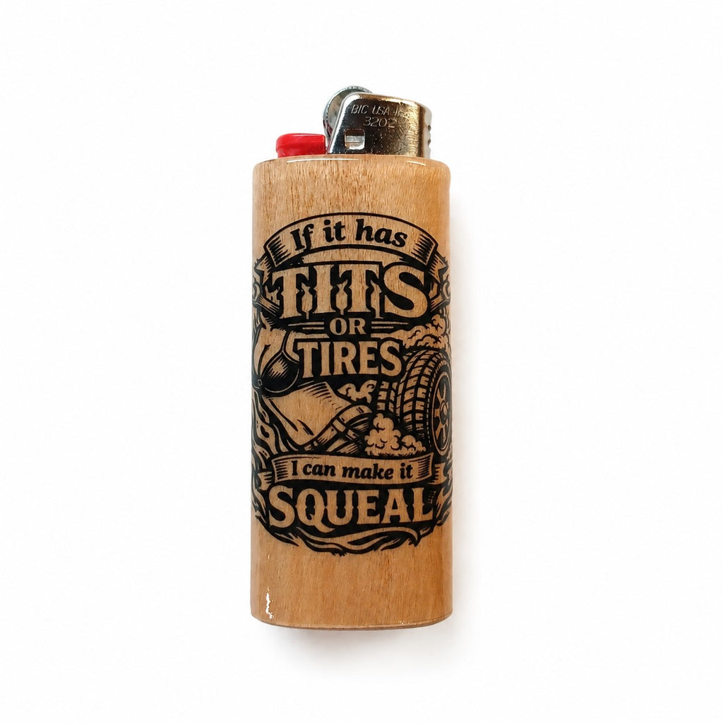 A light wood lighter with a black graphic print that reads 'If it has TITS or TIRES I can make it SQUEAL' alongside illustrations of a tire and a hand on a wrench. It features a red ignition button and a silver metal top.